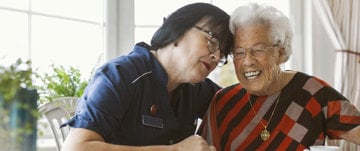 A smiling woman sits next to an older woman, representing the bond that strengthens healthy community ties.