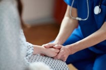 A compassionate nurse gently holds the hand of a patient, offering comfort and support in a healthcare setting.