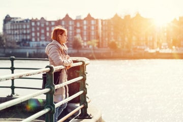 A woman relaxes on a railing, enjoying a peaceful view of the water ahead.