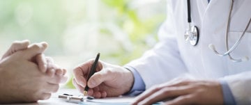 the doctor holds a pen in his hand and writes in the card