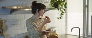 woman in the kitchen eating bread with jam for breakfast