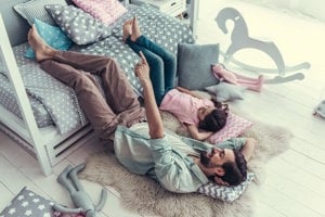 Father and daughter enjoying a moment of togetherness while lying on the floor.