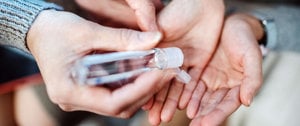 A person holding a bottle of hand sanitizer, emphasizing hygiene and health safety in everyday life.