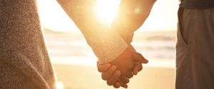 A couple walks hand in hand on the beach at sunset, reflecting their renewed intimacy despite facing prostate cancer.