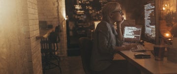 A woman working at a desk with a laptop, implementing techniques to cope with photophobia and migraine at home and work.