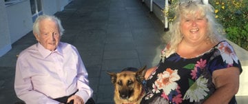 A senior man and woman share a moment with their dog, highlighting the bond of friendship and love in a serene environment.