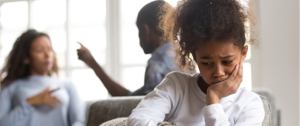 A young girl sits on a couch, hands on her face, reflecting her mental health struggles and desire for understanding from her parents.