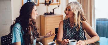 two women are talking and drinking coffee