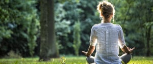  A woman in a field raises her hands, symbolizing self-care and resilience in managing MS and combating depression.