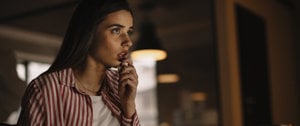 A woman in a red and white striped shirt watching a movie, reflecting on how a scary movie eased her anxiety.