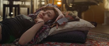 A woman lies on a rug with headphones, reflecting on the mental health effects of lockdown during her quiet moment.