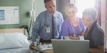 the medical staff looks at the laptop with a smile