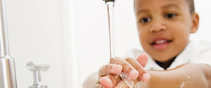 A young boy is engaged in washing his hands with soap, promoting fun and education in proper handwashing practices.