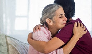  A woman embraces an older woman in a hospital room, conveying warmth and support during a challenging time.