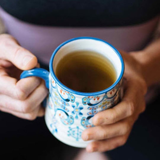 the woman is holding a cup of tea