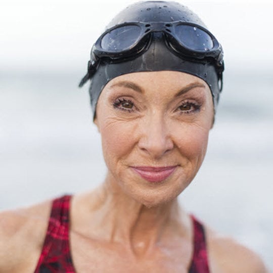 A woman in a swim cap and goggles prepares for a swim, showcasing readiness and focus in the water.