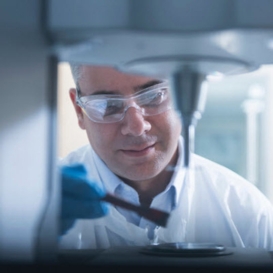 A man in a lab coat examines a machine, reflecting Teva's dedication to advancing biosimilars in healthcare.