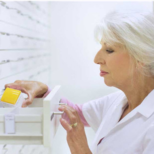 A woman in a white lab coat examines a cabinet, symbolizing research on biosimilars in the Canadian market.