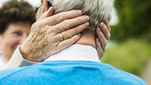 elderly woman's hands embrace gray man's head