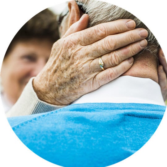 A close-up of an elderly woman gently resting her hand on man shoulder, conveying a sense of reflection and calmness.