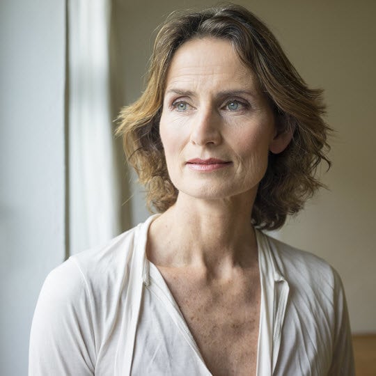 A woman with short hair dressed in a white shirt, exuding a sense of poise and professionalism.